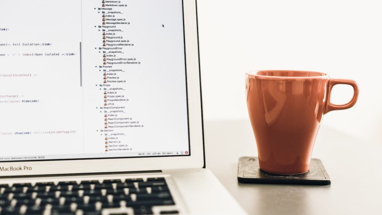turned on MacBook Pro near brown ceramic mug